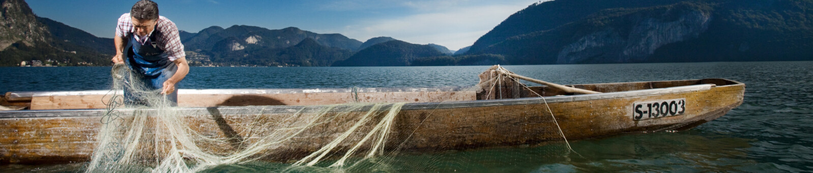    Fisherman with a net in a boat, SalzburgerLand 